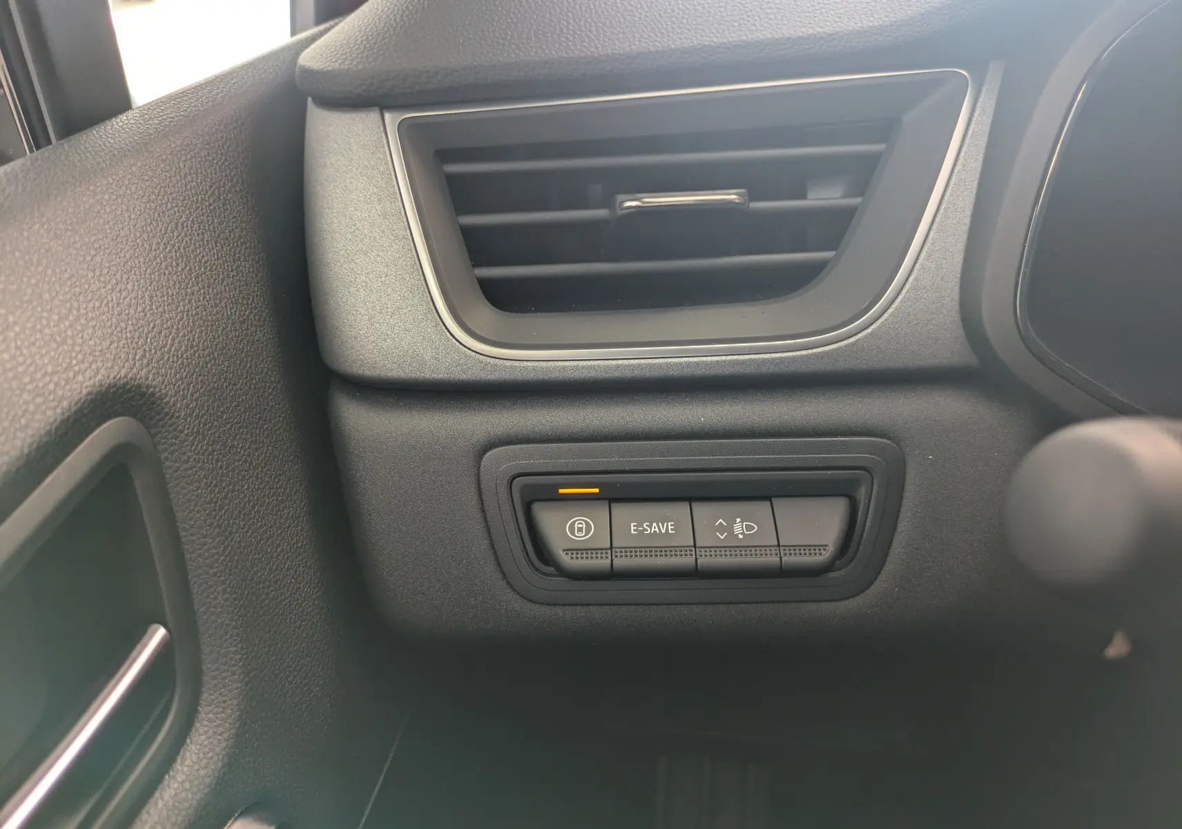 Détail des commandes E-SAVE et réglage des phares sous la sortie d'air côté gauche dans l'habitacle du Renault Captur hybride 2025.