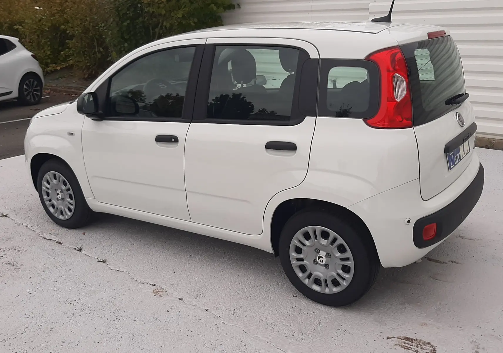 Vue 3/4 arrière droite d'une Fiat Panda 2025 blanc gelato, compacte et cinq portes, avec feux arrière rouges distinctifs.