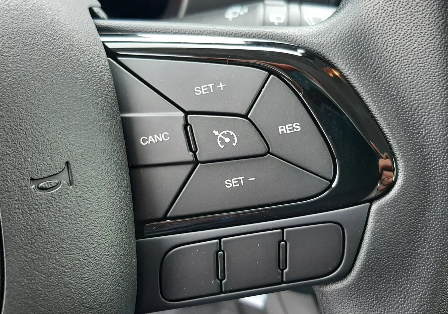 Gros plan sur les commandes de régulateur de vitesse au volant de la Fiat Panda 2025, finition noire.