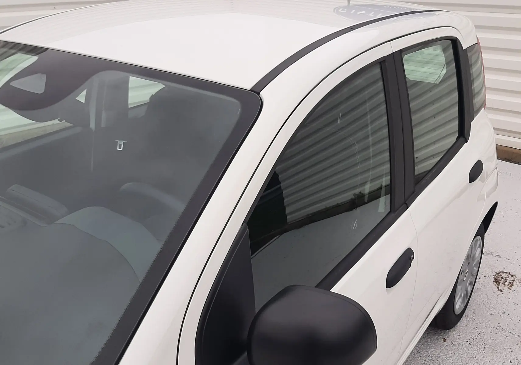Vue 3/4 avant droit d'une Fiat Panda 2025 blanc gelato avec rétroviseur noir mat et vitres teintées.