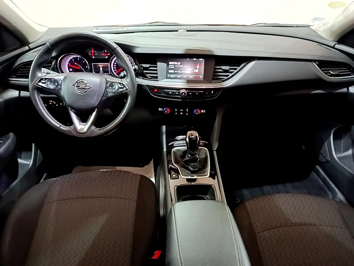 Vue intérieure avant de l'Opel Insignia 2019, tableau de bord noir avec écran tactile et volant cuir multifonctions.