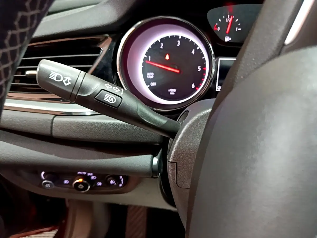 Vue rapprochée du commodo gauche et du compte-tours éclairé de l’Opel Insignia 1.6 Diesel rouge, tableau de bord sombre.