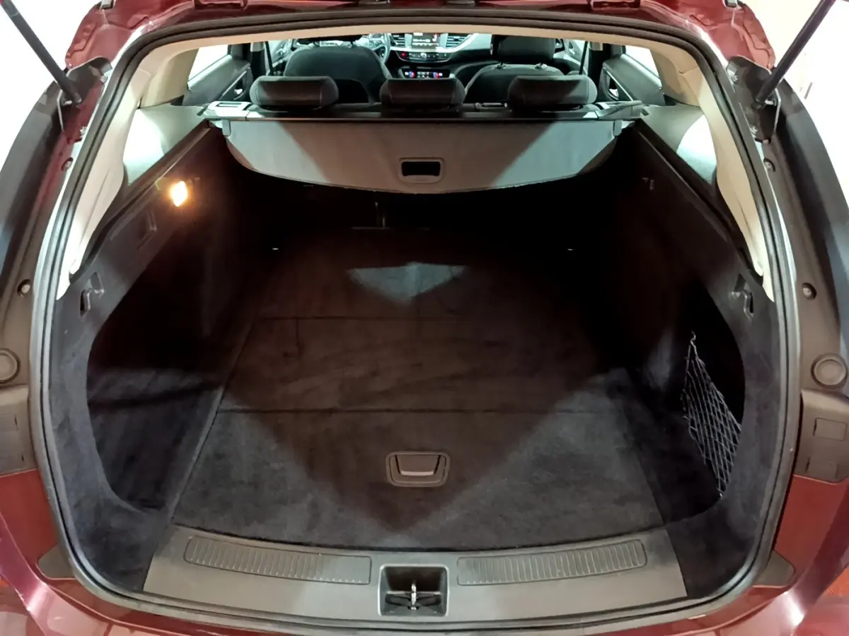 Vue arrière du coffre ouvert de l’Opel Insignia rouge, montrant un espace de chargement spacieux et propre.