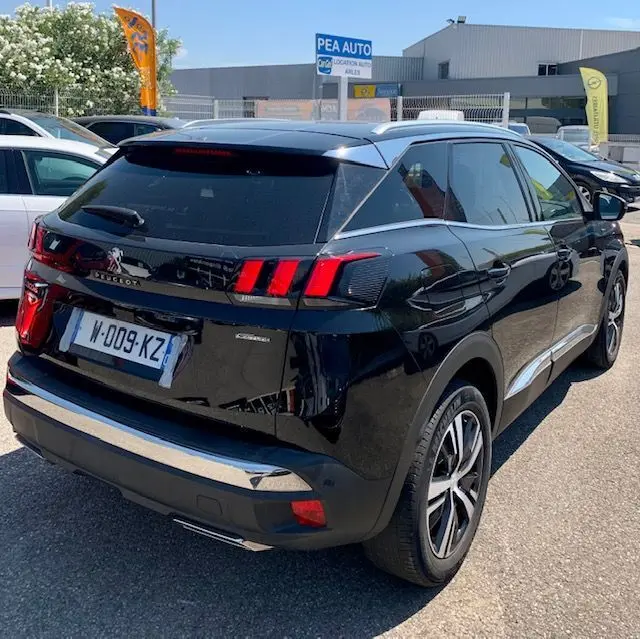 Vue 3/4 arrière droite d'un Peugeot 3008 noir de 2018 avec feux arrière à griffes et jantes alliage distinctives.