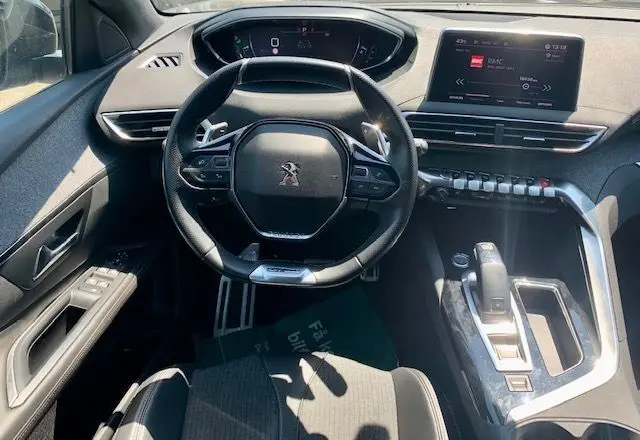 Vue intérieure du poste de conduite du Peugeot 3008 noir 2018, avec volant compact et écran tactile central allumé.