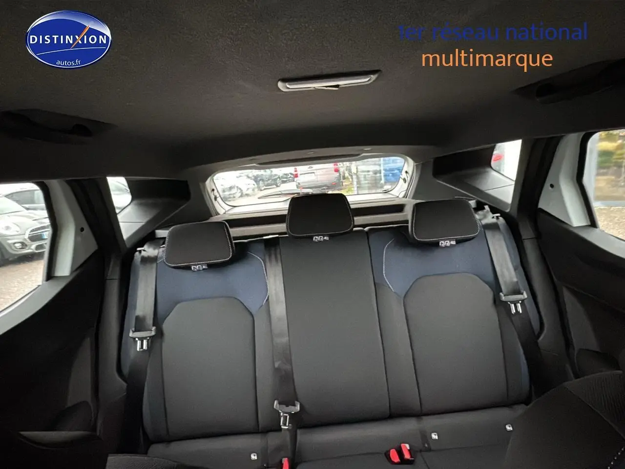 Vue arrière intérieure du Dacia Duster 2025 blanc arctic, montrant la banquette 3 places avec appuie-têtes et ceintures.