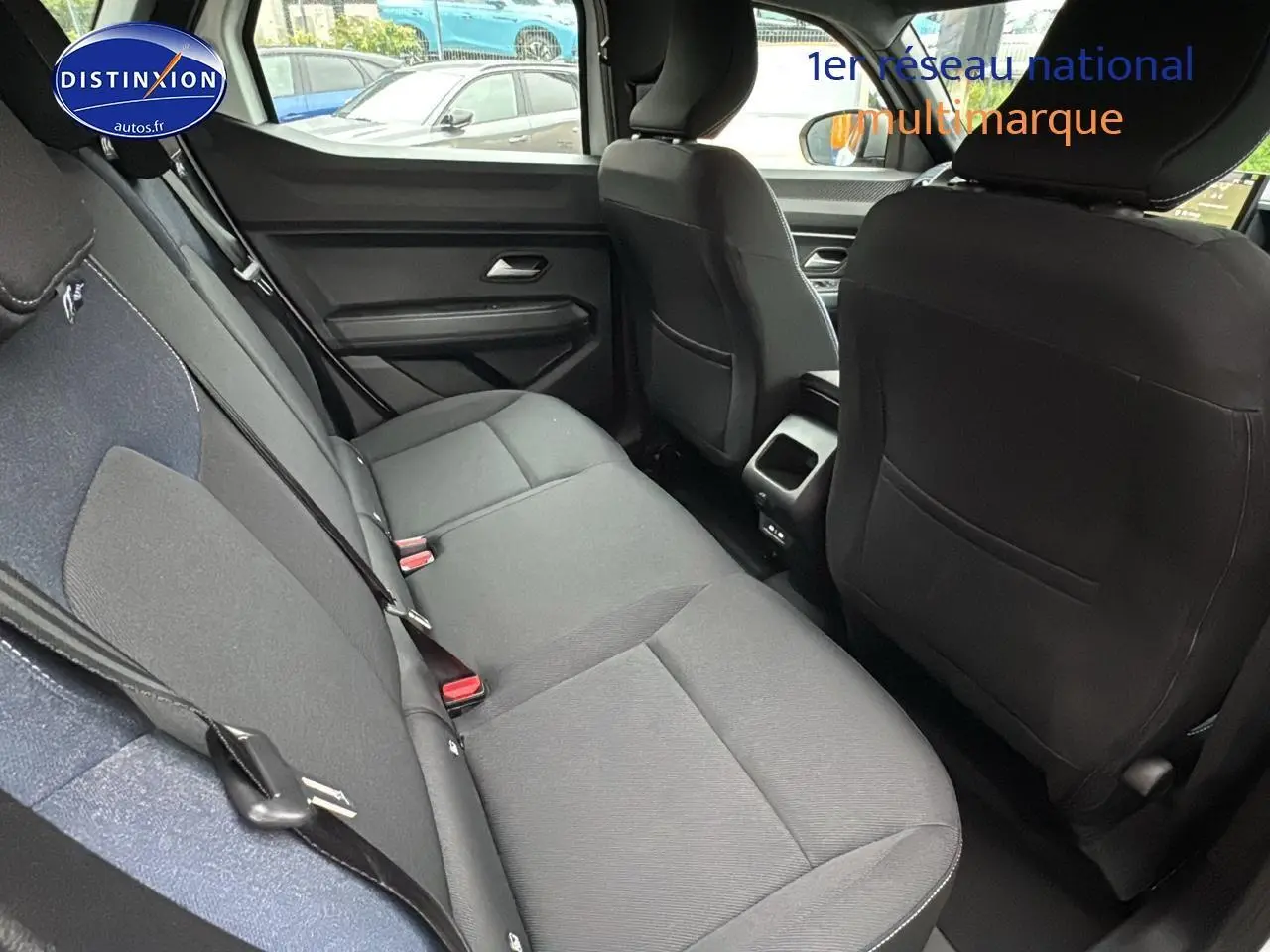 Vue intérieure arrière côté gauche du Dacia Duster 2025 blanc arctic, montrant la banquette et les sièges avant noirs.