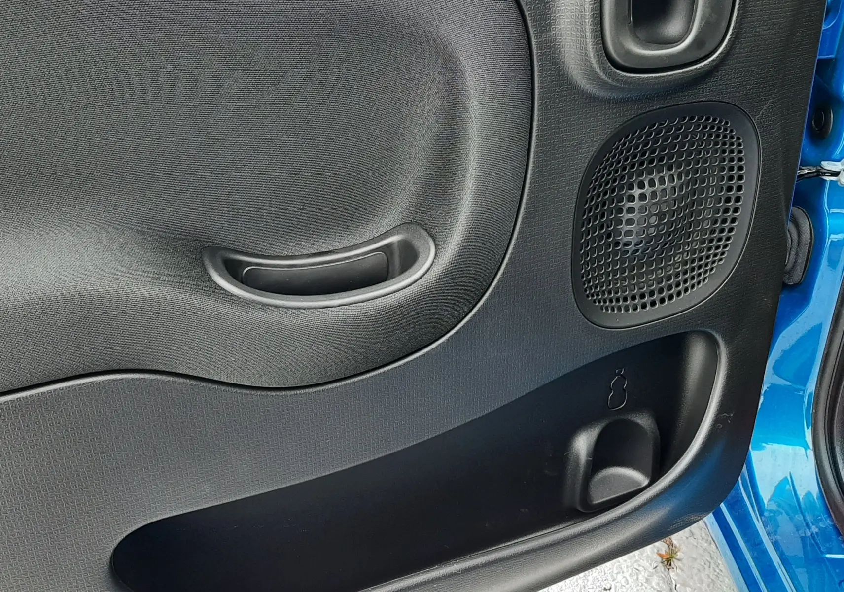 Gros plan sur la porte avant droite noire de la Fiat Panda Bleu Italia avec haut-parleur et poignée intégrée.