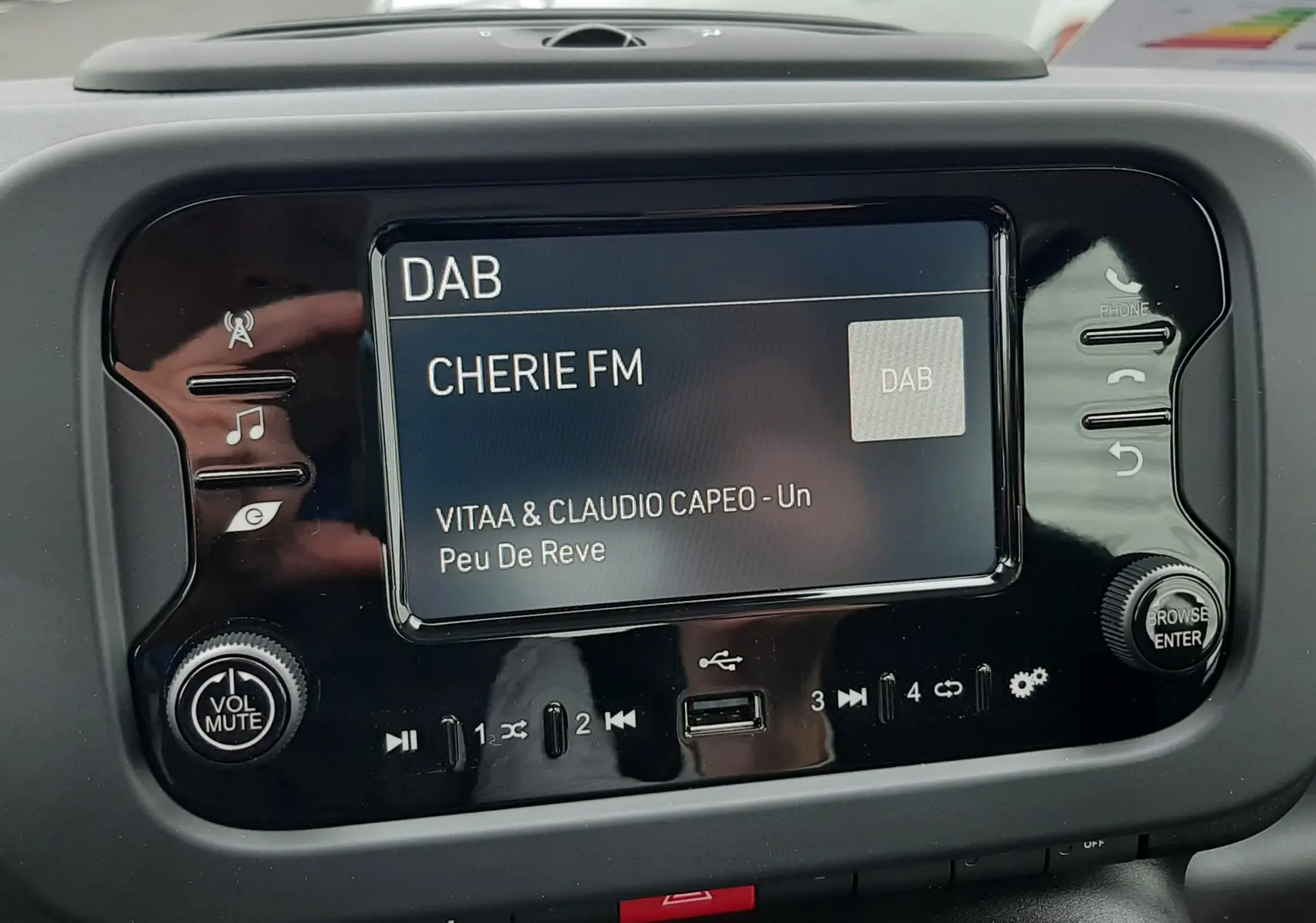 Gros plan sur l'écran multimédia de la Fiat Panda 2025, affichant la radio DAB sur CHERIE FM avec commandes tactiles noires.