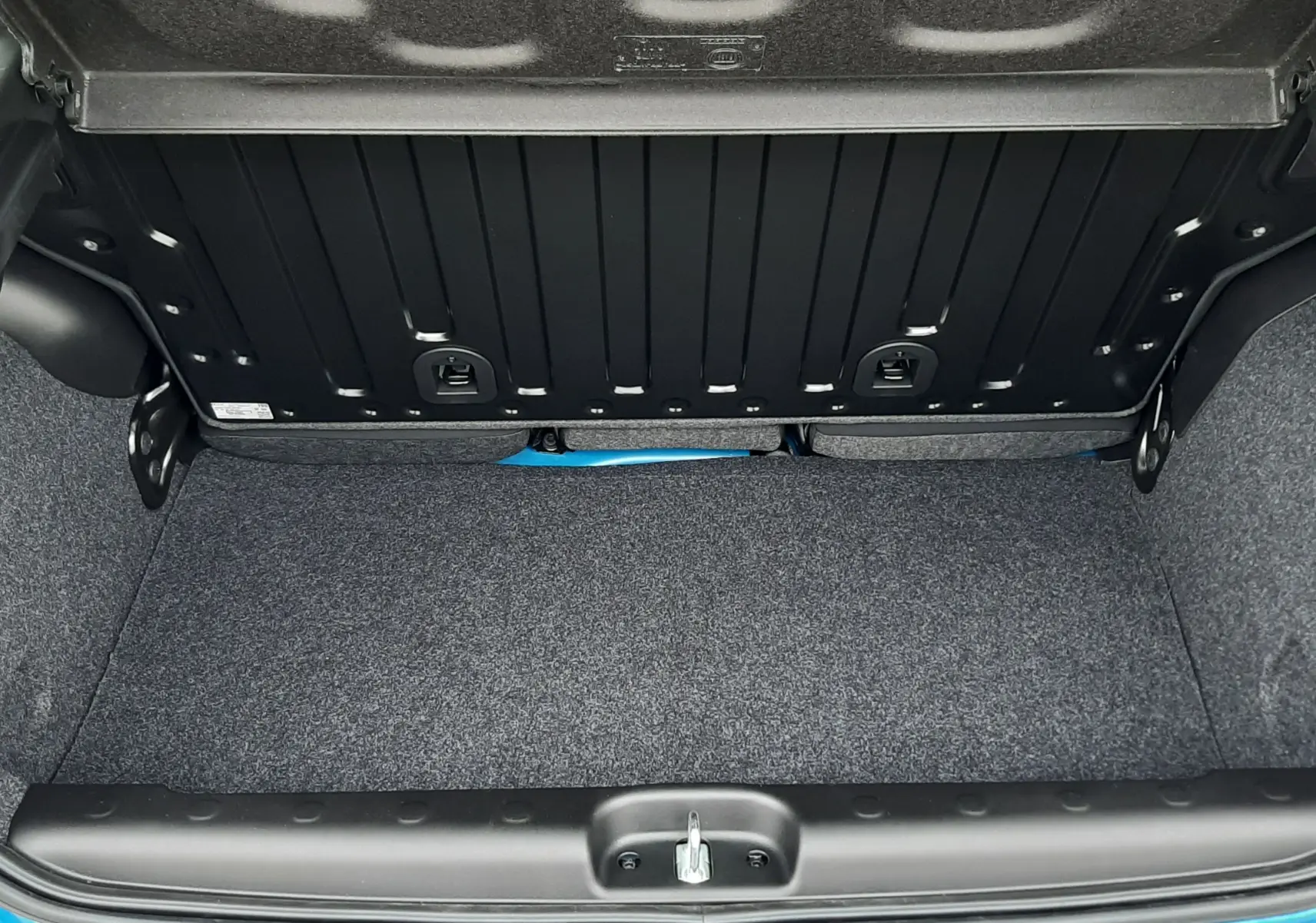Coffre ouvert vu de dessus d'une Fiat Panda 2025 bleu Italia, montrant le tapis gris et la bordure de coffre.