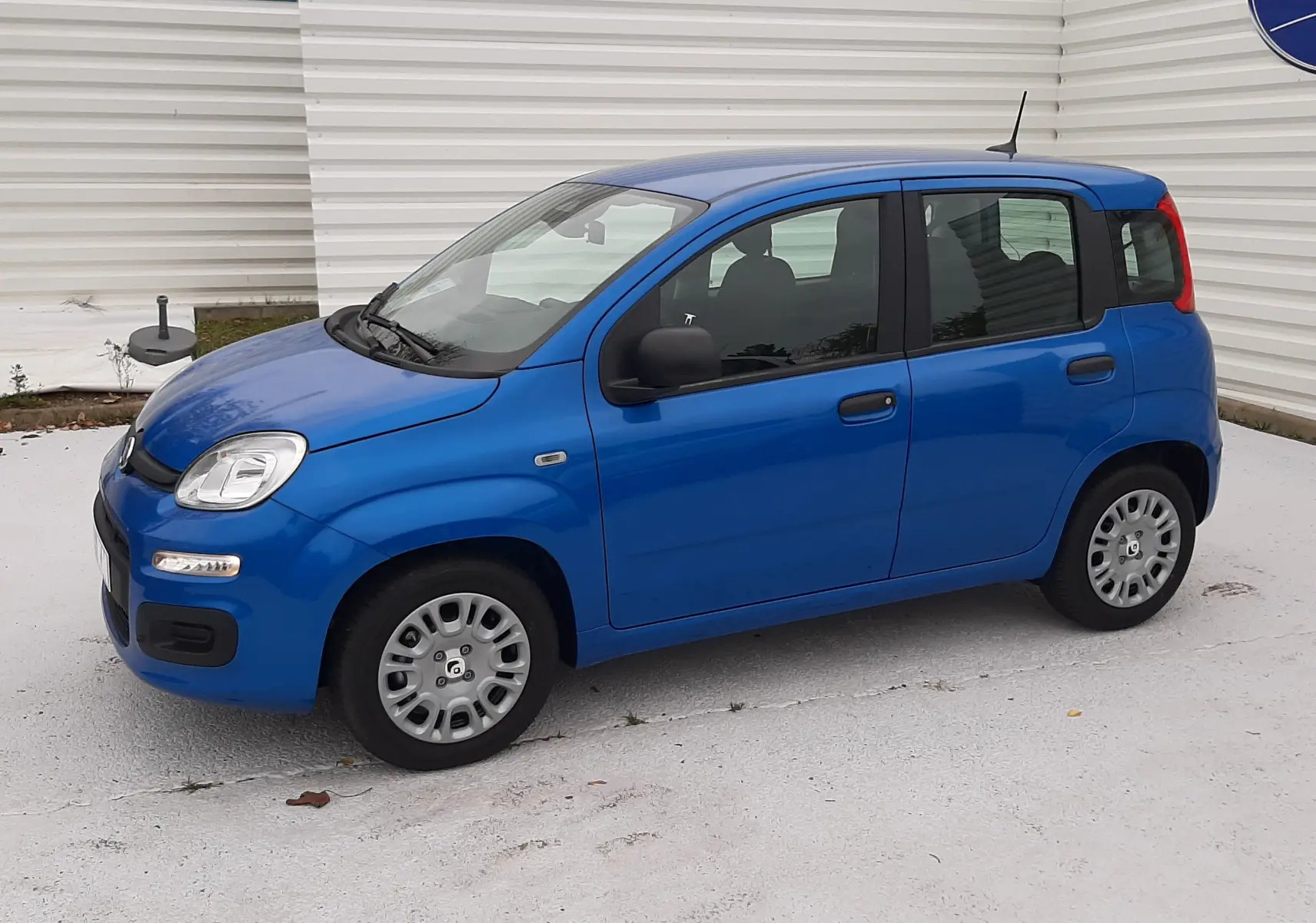 Vue de profil côté gauche d'une FIAT Panda 2025 bleu Italia à cinq portes, avec rétroviseurs noirs et jantes acier.