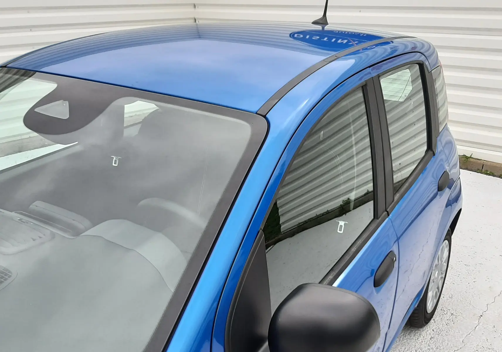 Vue 3/4 avant droit d'une Fiat Panda 2025 bleu Italia, avec rétroviseur noir et vitrage teinté.