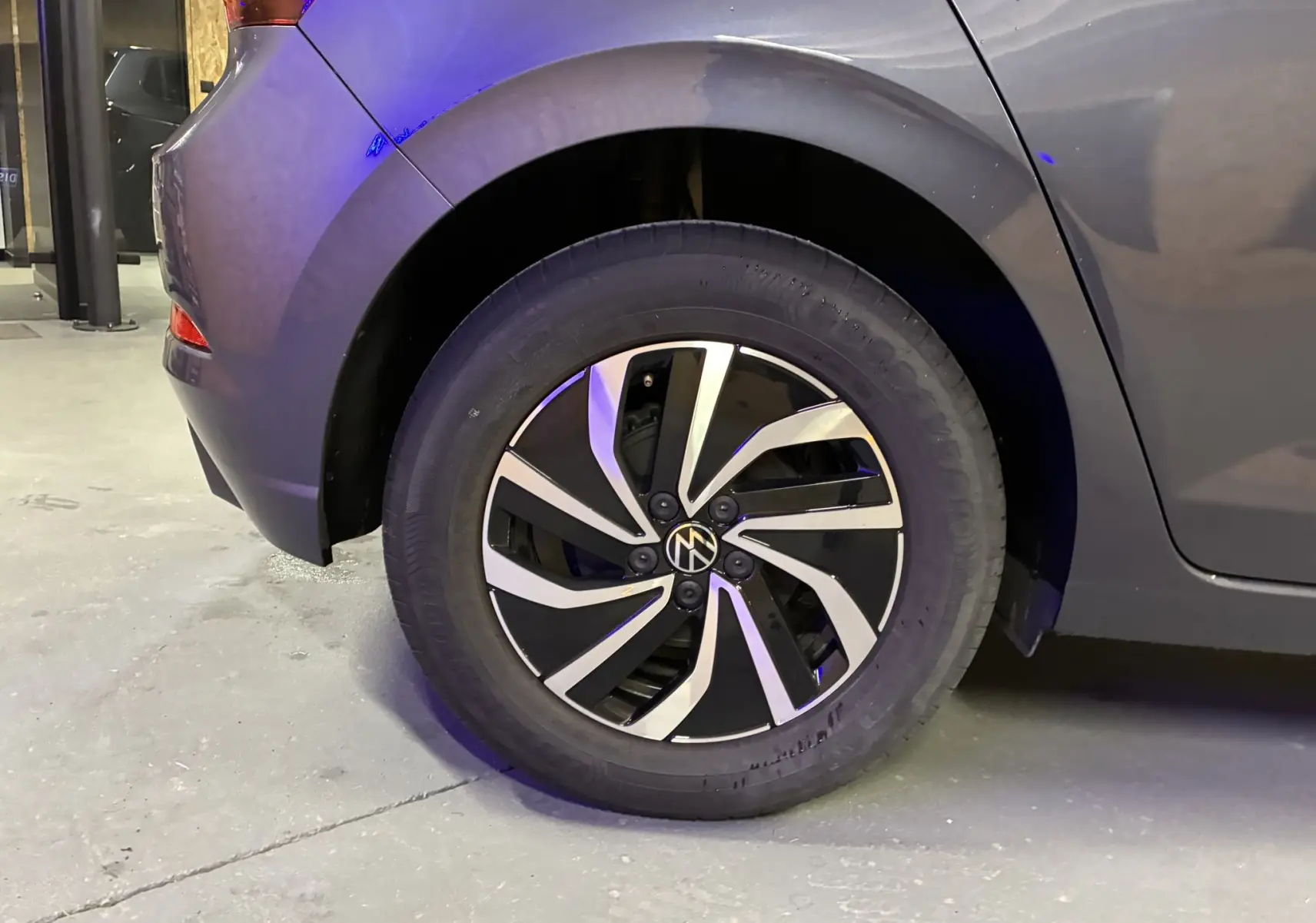 Gros plan sur la roue arrière gauche d'une Volkswagen Polo gris métallisé avec jante alliage bicolore moderne.