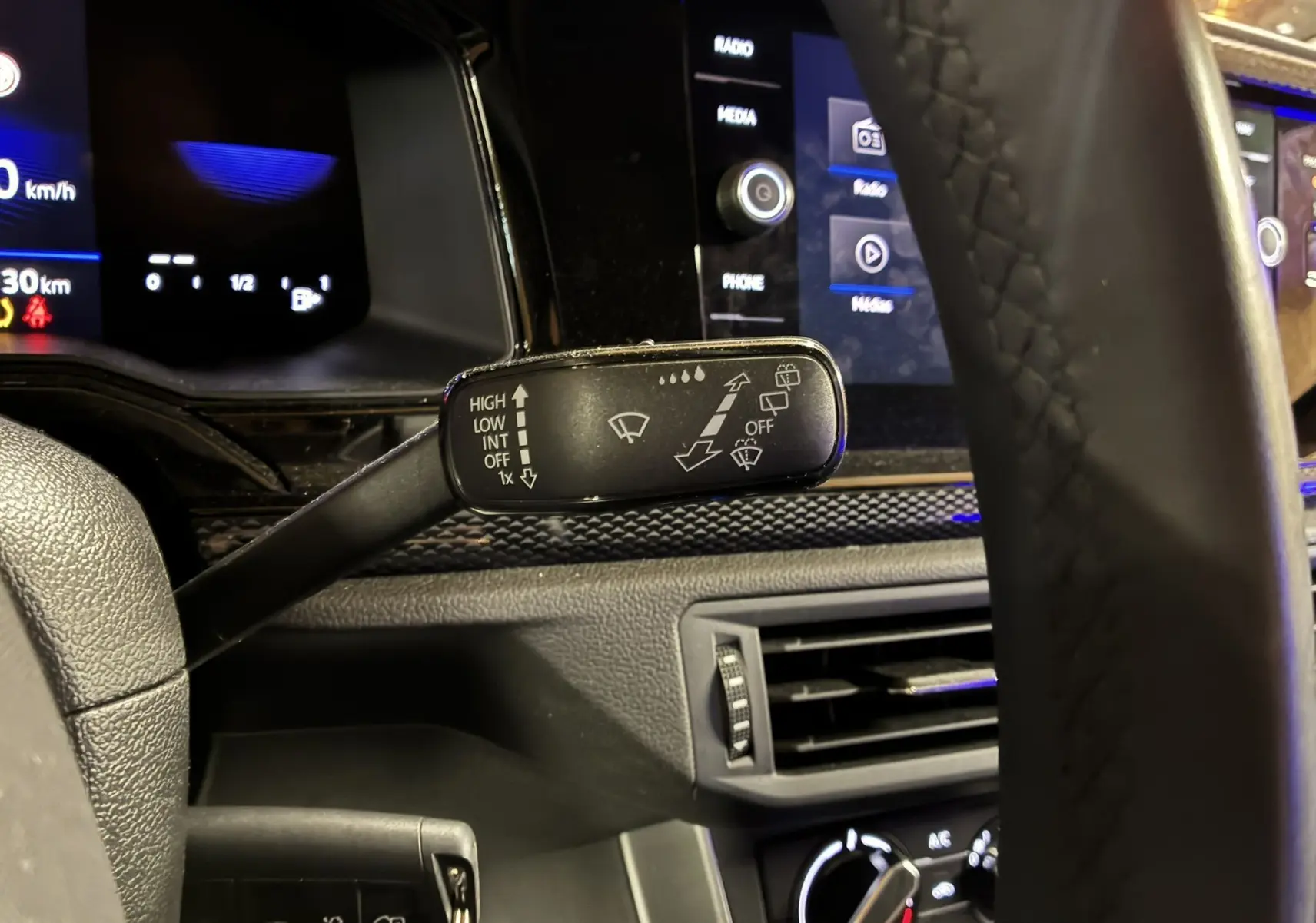 Gros plan sur la commande d’essuie-glace à gauche du volant dans l’habitacle noir d’une Volkswagen Polo gris 2025.