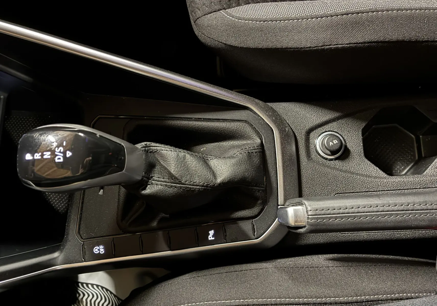 Gros plan sur la commande de boîte automatique et frein à main dans l'habitacle noir d'une Volkswagen Polo gris 2025.