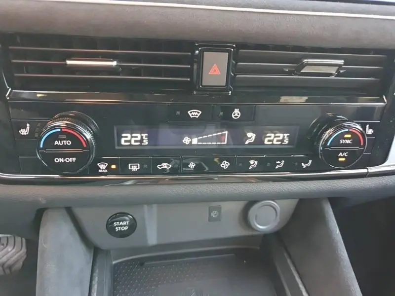 Tableau de bord du Nissan Qashqai Hybrid e-POWER 2025 montrant la climatisation bi-zone avec réglages à 22°C et boutons noirs.