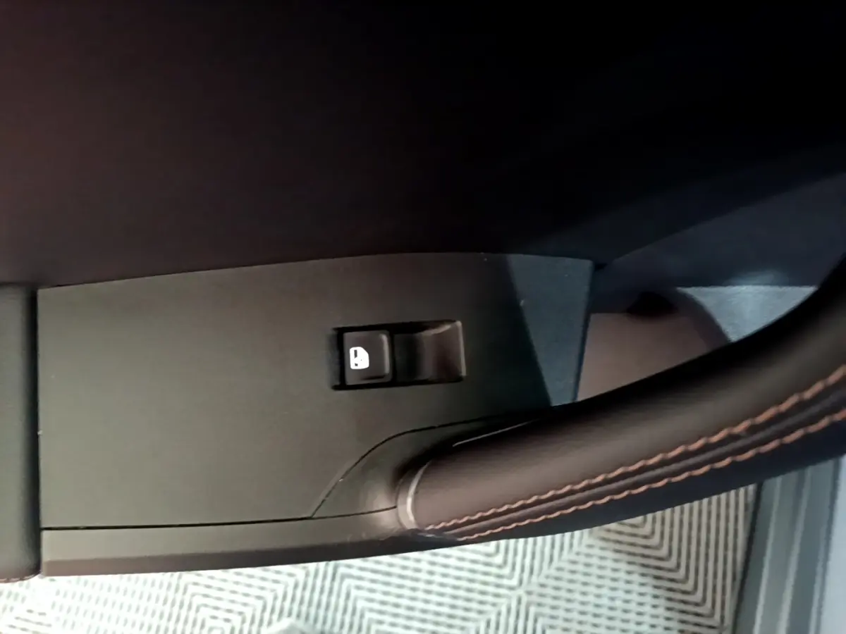 Gros plan sur le bouton de verrouillage des portes, avec poignée en cuir noir sur portière d'une CUPRA Formentor gris foncé.