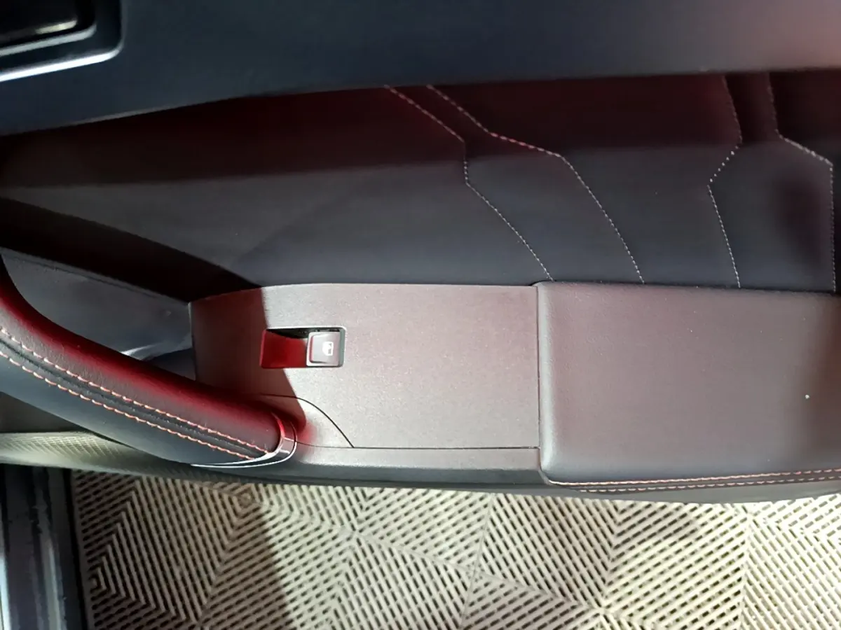 Détail de la porte intérieure côté gauche du CUPRA Formentor gris foncé avec surpiqûres rouges et bouton de verrouillage.