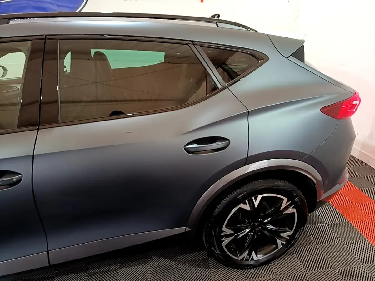 Vue latérale côté droit d'un CUPRA Formentor gris foncé 2024, mettant en valeur la roue arrière et la ligne de caisse dynamique.