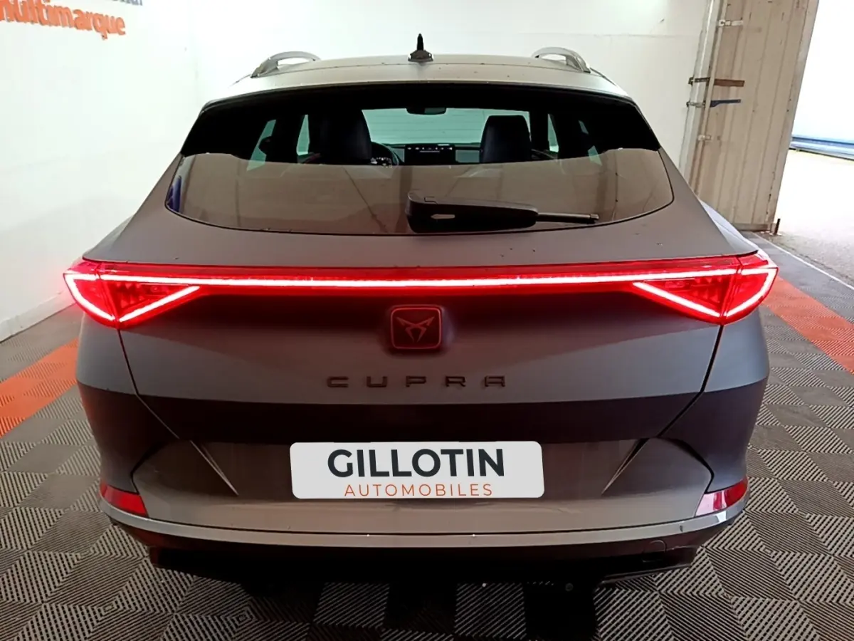 Vue arrière d'une CUPRA Formentor gris foncé 2024 avec feux LED allumés et logo central lumineux.
