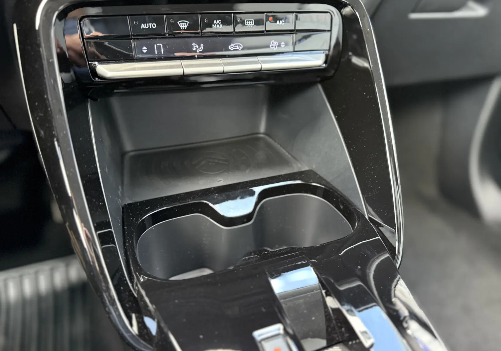 Gros plan sur la console centrale noire du Citroën C3 Aircross Hybrid 145, avec commandes climatisation et porte-gobelets.