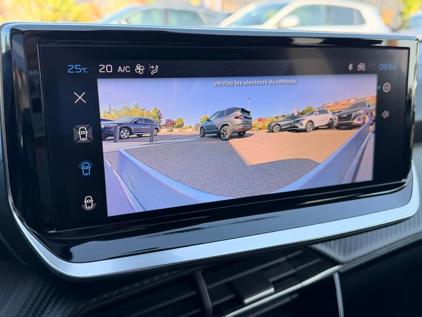 Écran tactile intérieur montrant la caméra de recul avec vue arrière sur plusieurs SUV stationnés en extérieur.