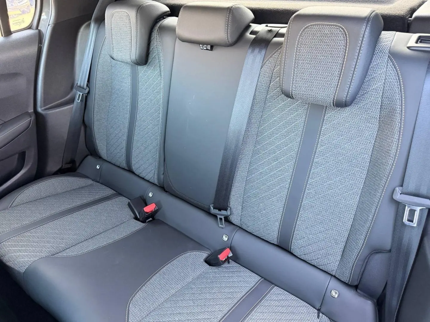 Vue rapprochée de la banquette arrière grise tissu et cuir de la Peugeot 208 1.2 100ch Allure, avec appuie-têtes et ceintures visibles.