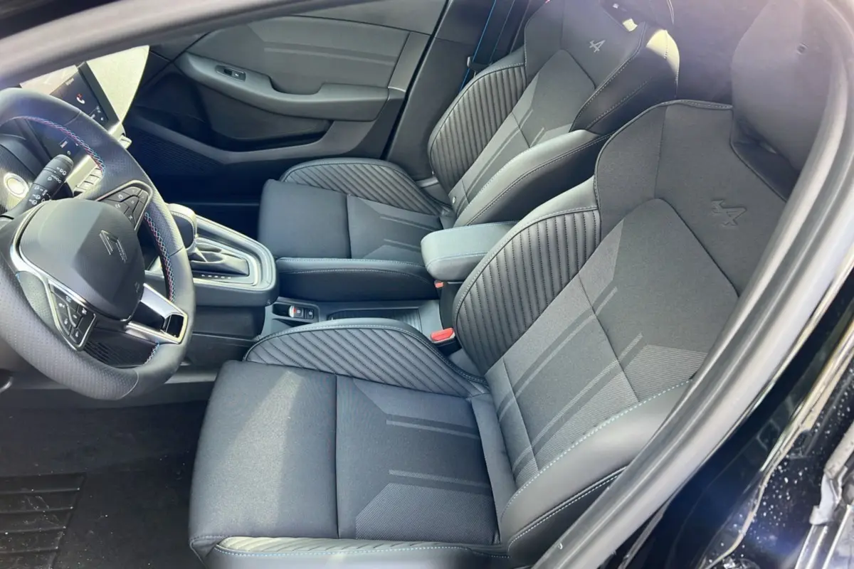 Intérieur de la Renault Clio V E-Tech 145 Esprit Alpine 2025, vue côté conducteur, sièges noirs étoilés avec logo Alpine brodé.