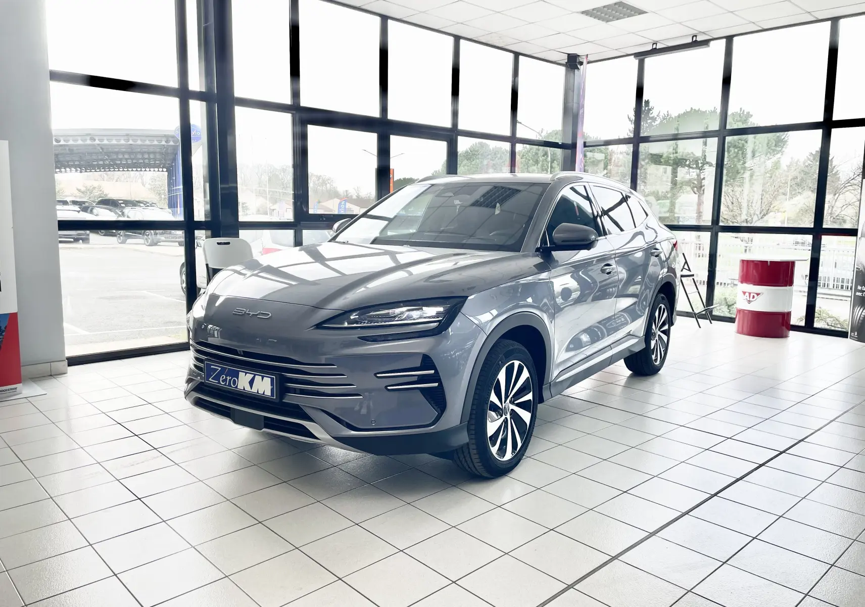 Vue 3/4 avant droite du BYD SEAL U gris TIME GREY, hybride rechargeable, avec jantes alliage bicolores en showroom lumineux.