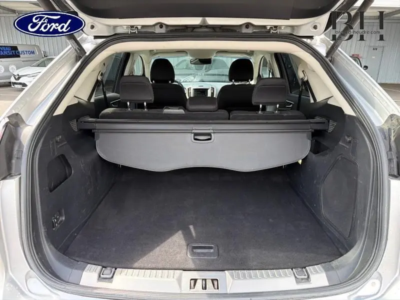 Vue arrière du coffre ouvert du Ford Edge gris Ingot, montrant l'espace de chargement et la plage arrière.