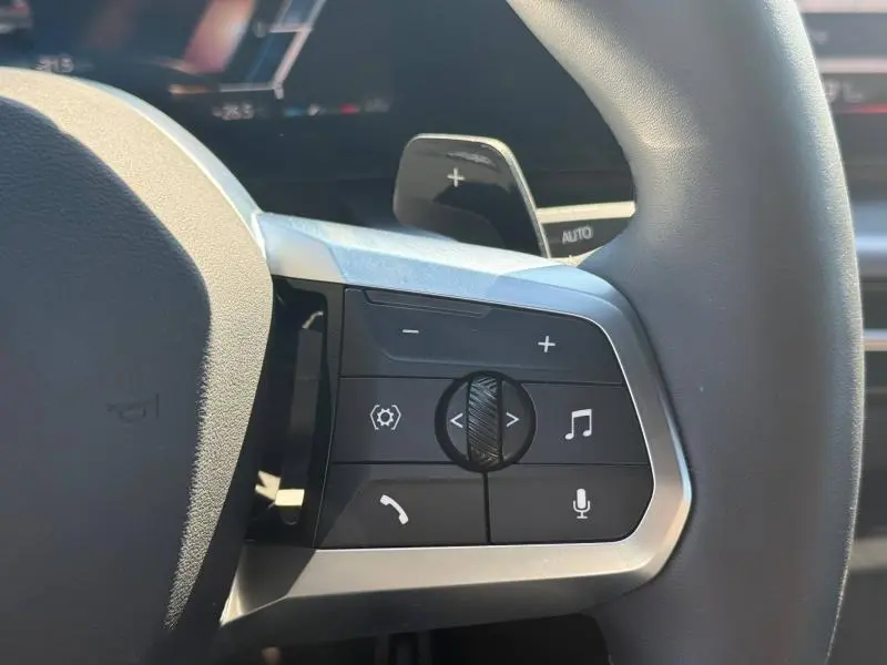 Gros plan sur les commandes multifonctions au volant cuir du BMW X2 Skyscraper Grey, avec palettes de changement de vitesses visibles.