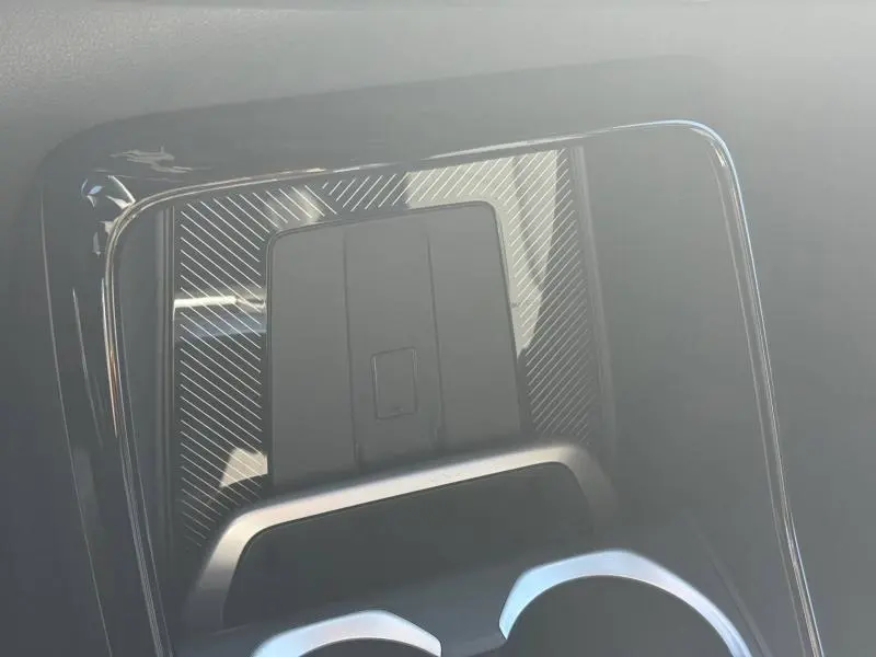 Gros plan sur la console centrale du BMW X2 2025, finition M Sport, avec surface noire texturée et porte-gobelets visibles.