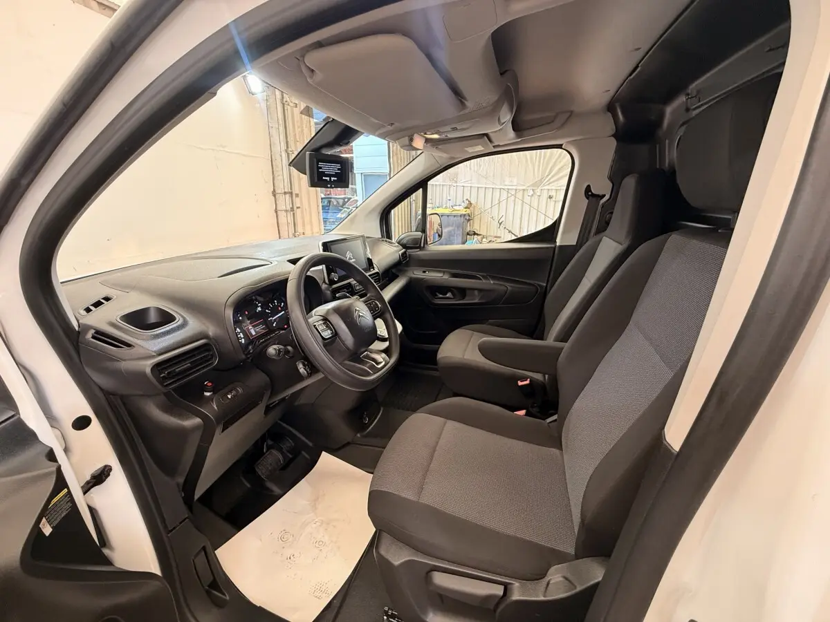 Intérieur côté conducteur du Citroën Berlingo blanc 2022, montrant les sièges et le tableau de bord moderne.