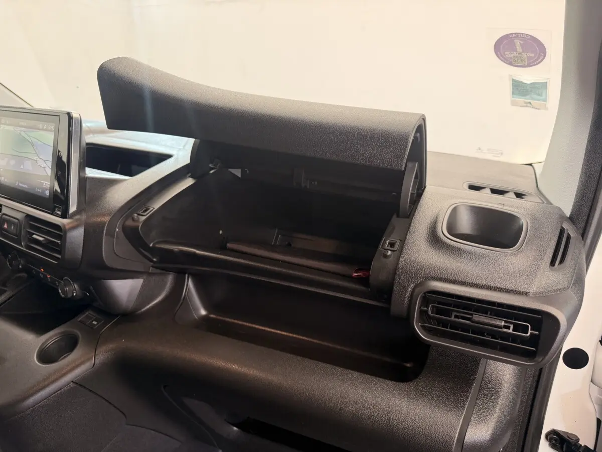 Intérieur du Citroën Berlingo 2022 blanc, vue côté passager avec boîte à gants ouverte et tableau de bord noir.