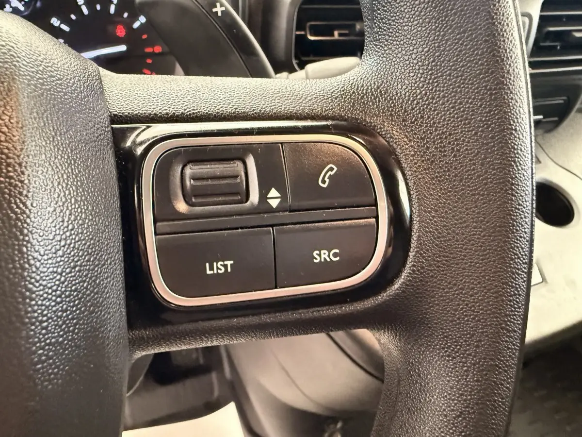 Gros plan sur les commandes gauche du volant noir du Citroën Berlingo 2022, boutons de gestion audio et appel.