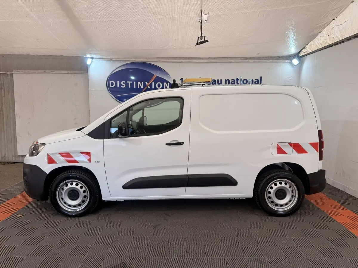 Profil droit d’un utilitaire Citroën Berlingo blanc 2022 avec bandes réfléchissantes rouges et blanches sur ailes avant et arrière.