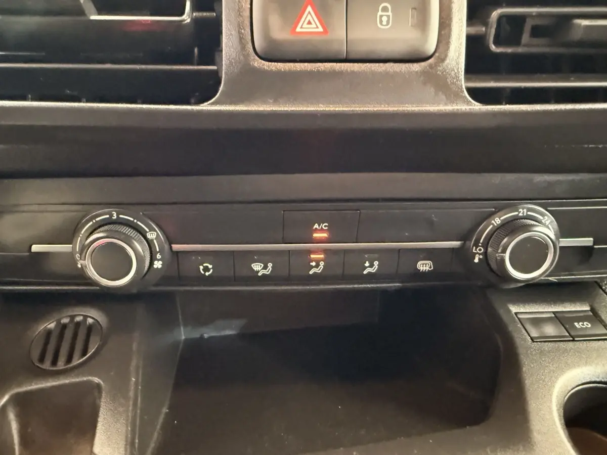 Vue rapprochée du tableau de bord noir du Citroën Berlingo 2022, avec commandes climatisation et bouton A/C allumé.