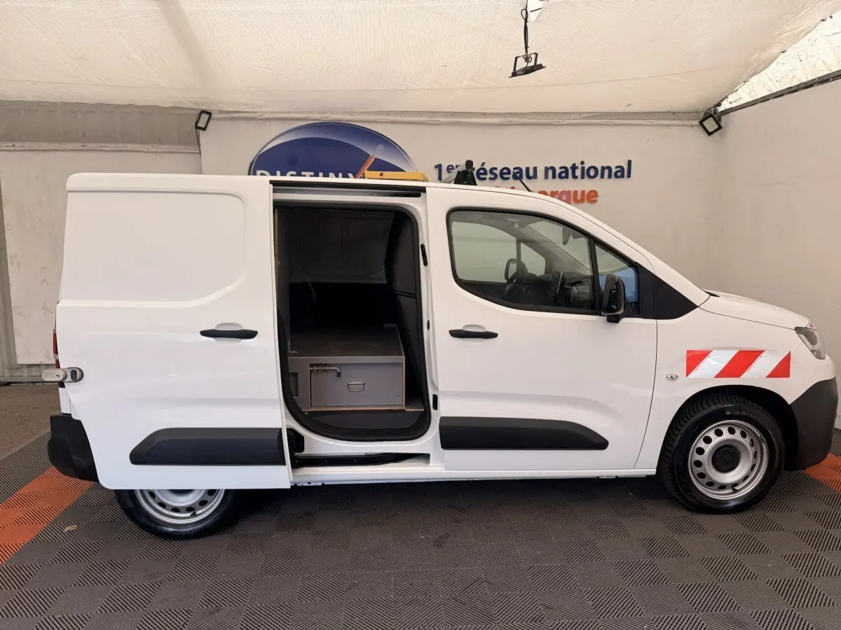 Vue latérale droite d’un Citroën Berlingo blanc 2022 avec porte coulissante ouverte et marquage rouge réfléchissant sur l’aile avant.