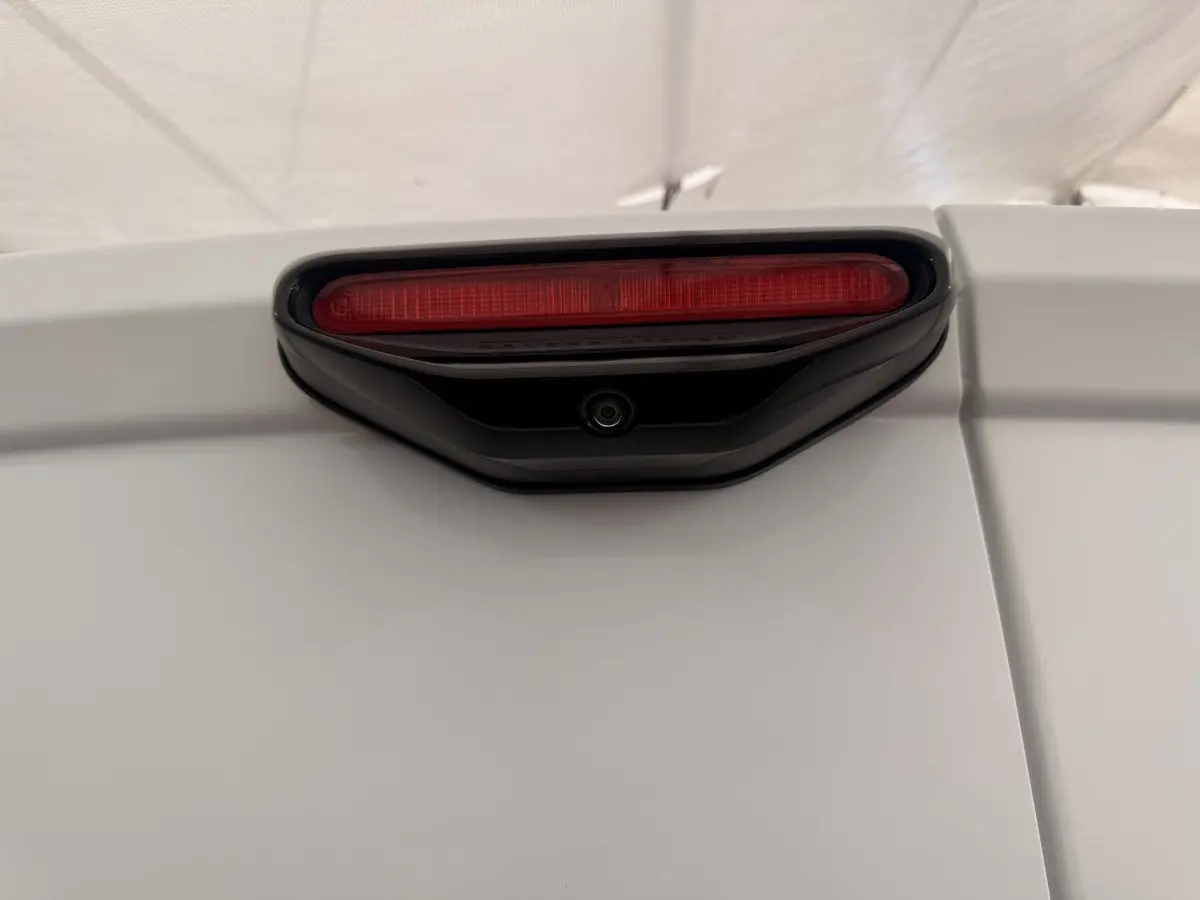 Gros plan sur le feu stop arrière rouge et la caméra de recul intégrée sur la porte blanche d'un Citroën Berlingo 2022.