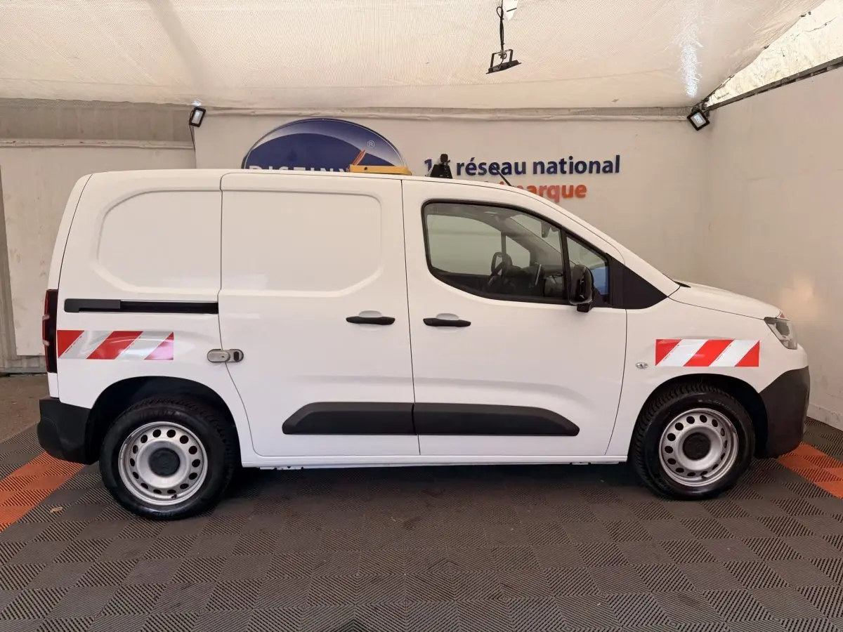 Vue de profil côté droit d’un Citroën Berlingo blanc 2022 avec bandes réfléchissantes rouges sur ailes avant et arrière.