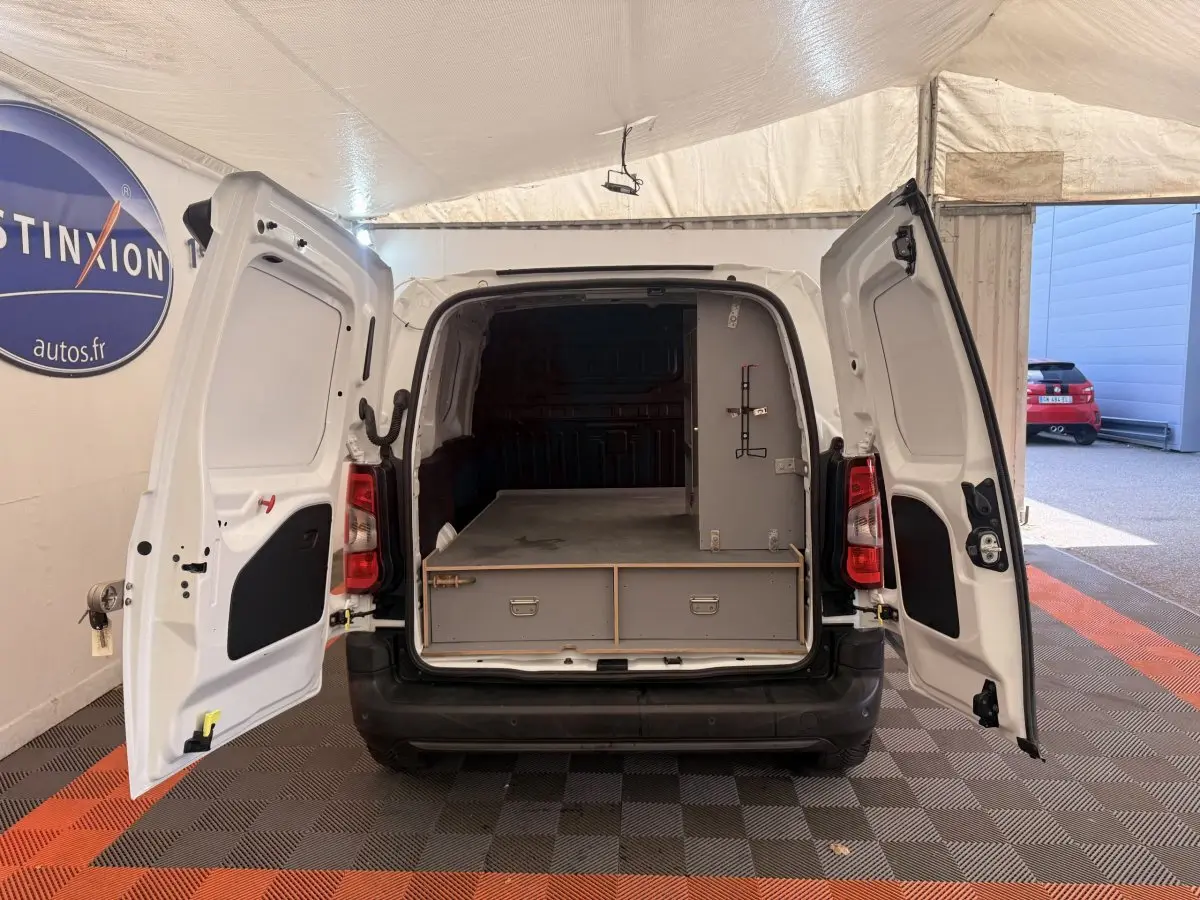 Vue arrière d’un Citroën Berlingo blanc 2022 avec portes ouvertes montrant l’espace de chargement aménagé.
