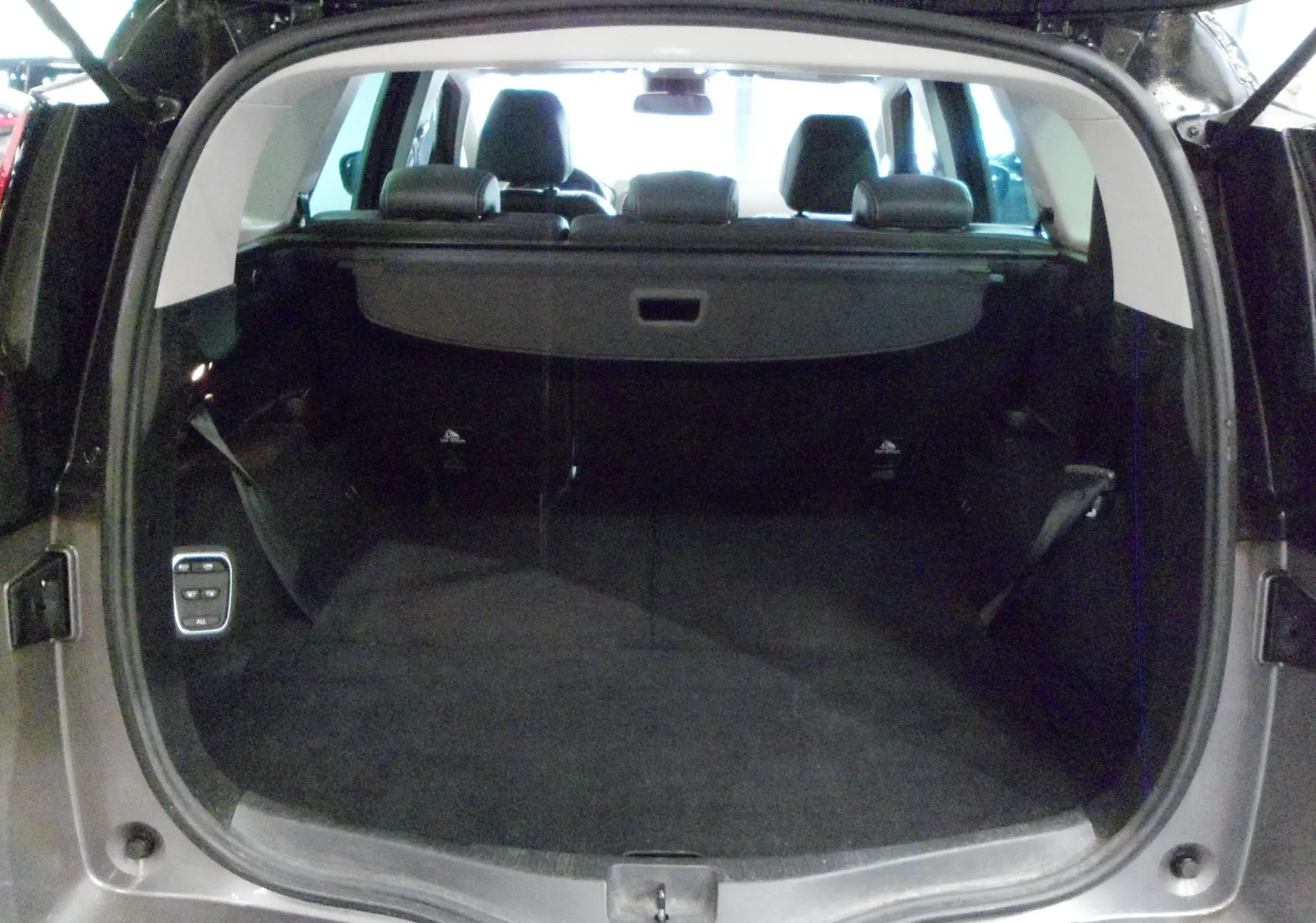 Coffre ouvert vu de l'arrière d'un Renault Grand Scenic IV gris Cassiopé avec intérieur noir et banquettes rabattues.