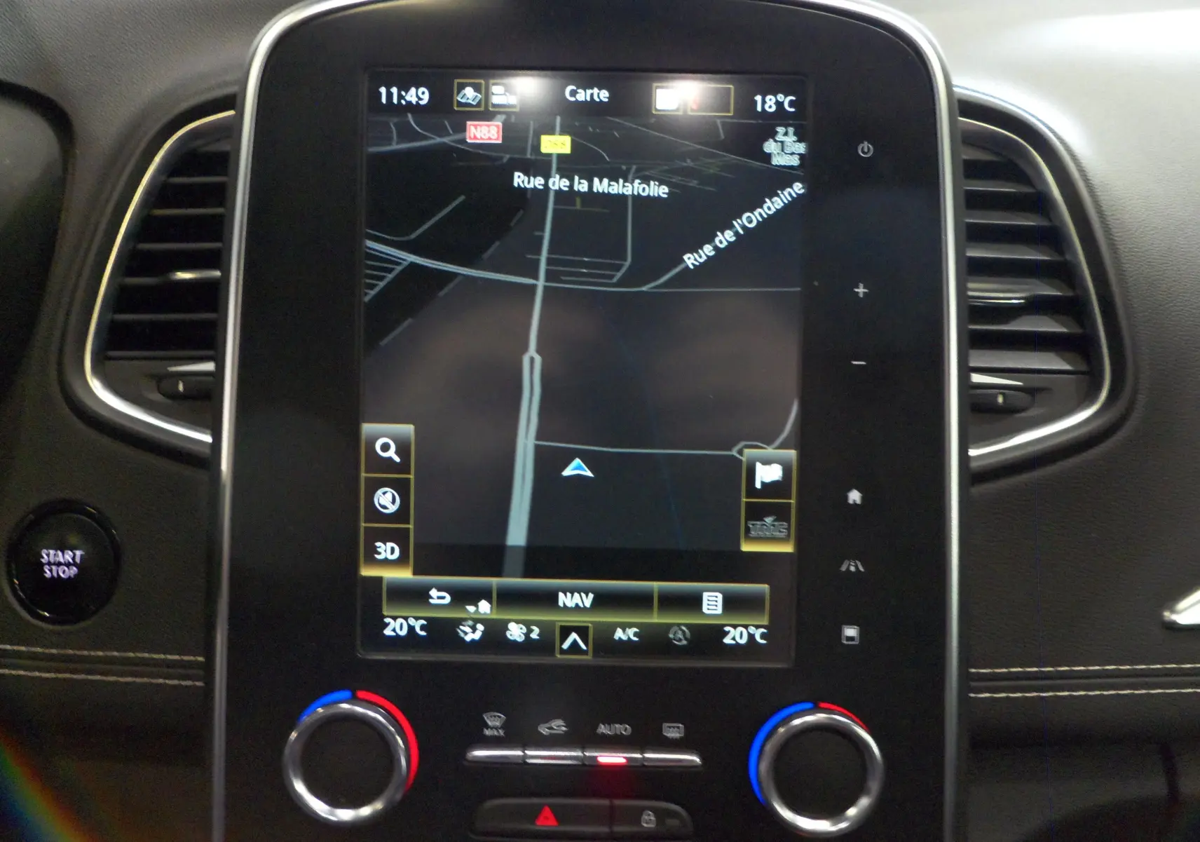 Vue rapprochée de l’écran tactile central du Renault Grand Scenic IV avec navigation affichée et commandes climatisation.