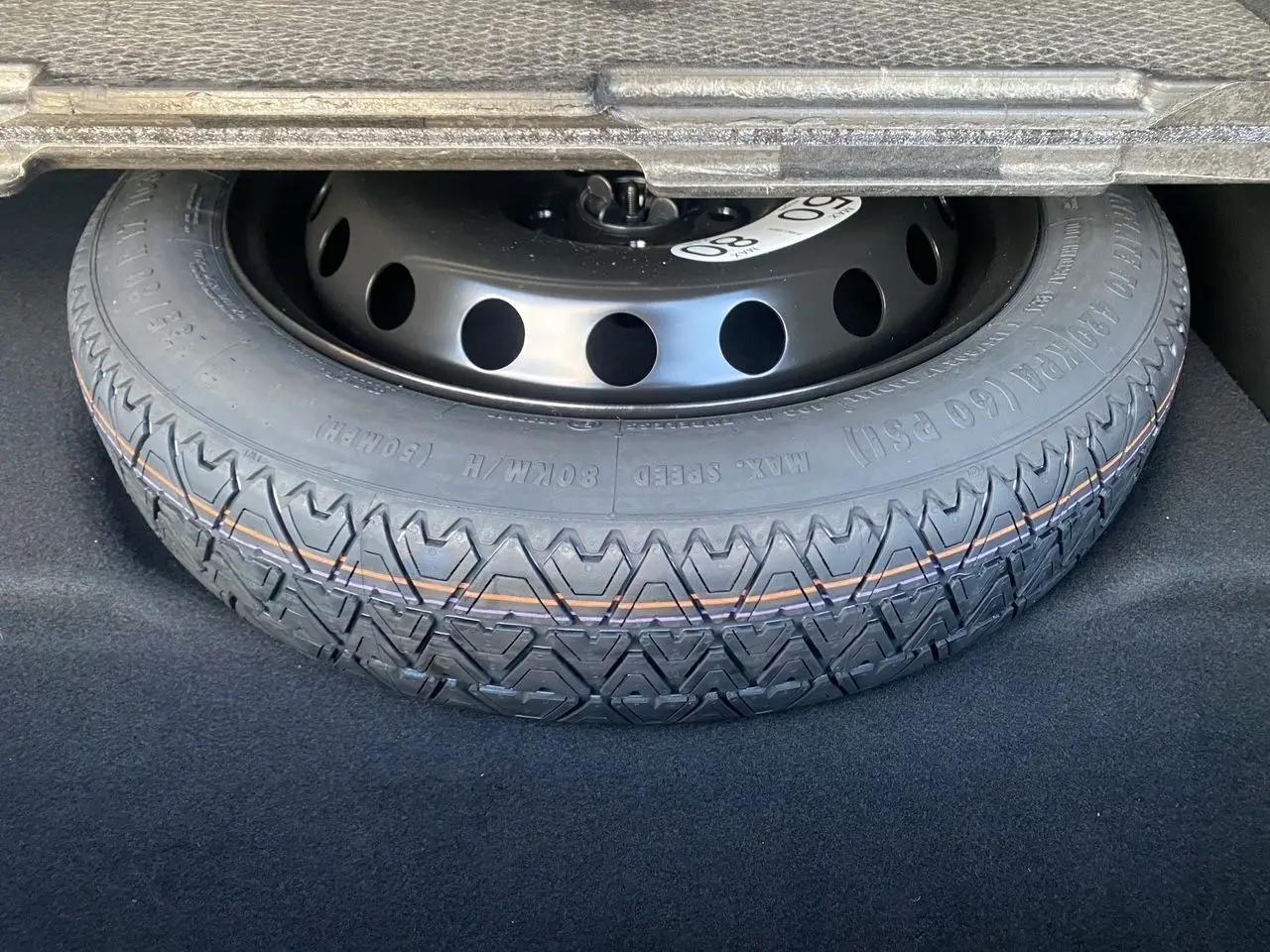 Gros plan sur la roue de secours temporaire noire dans le coffre d'une Renault SYMBIOZ hybride 2025.