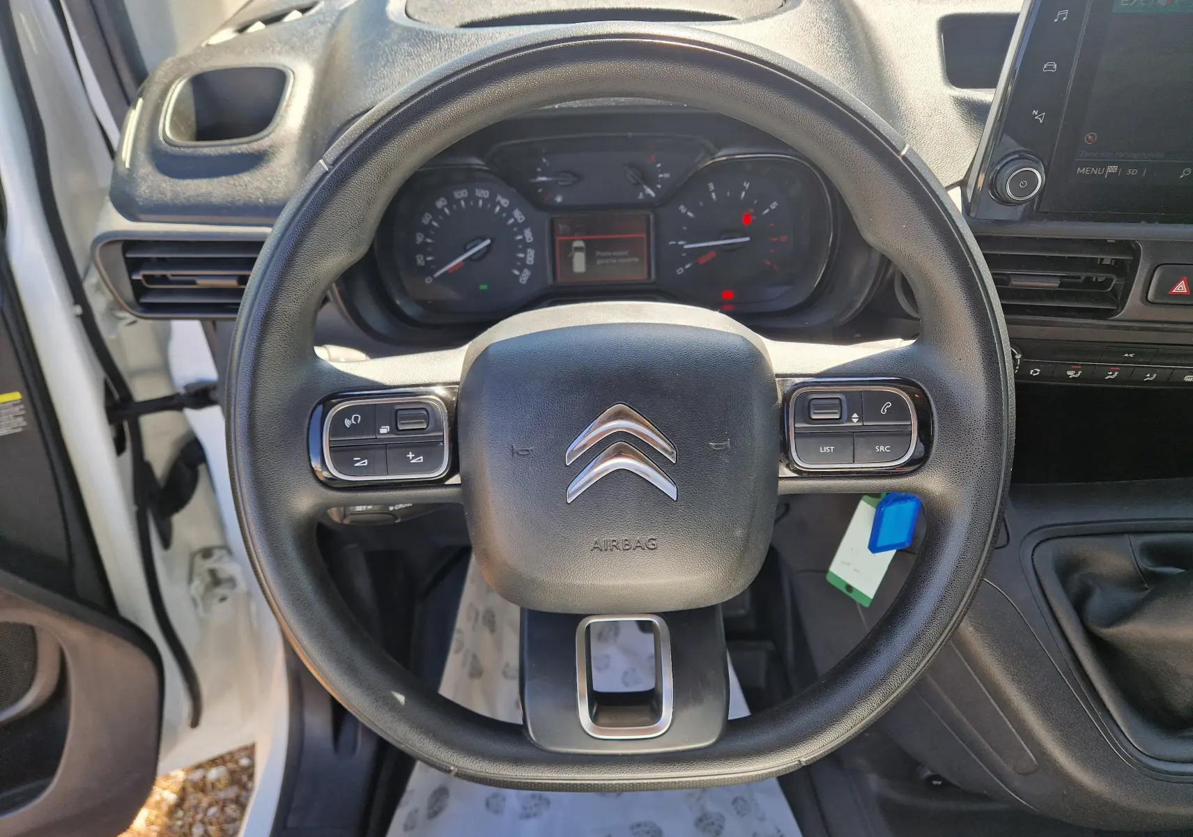 Vue intérieure centrée sur le volant noir du Citroën Berlingo blanc 2020 avec tableau de bord et commandes au volant visibles.