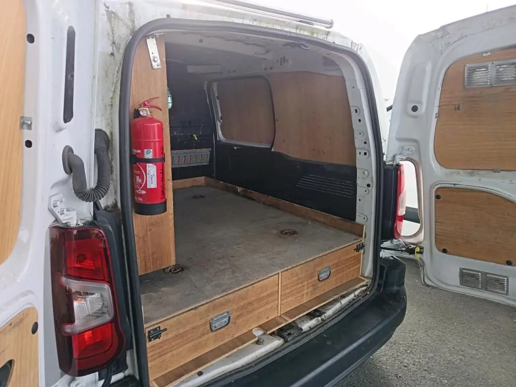 Vue arrière ouverte du Citroën Berlingo blanc 2020, montrant l’aménagement bois intérieur avec extincteur fixé côté gauche.