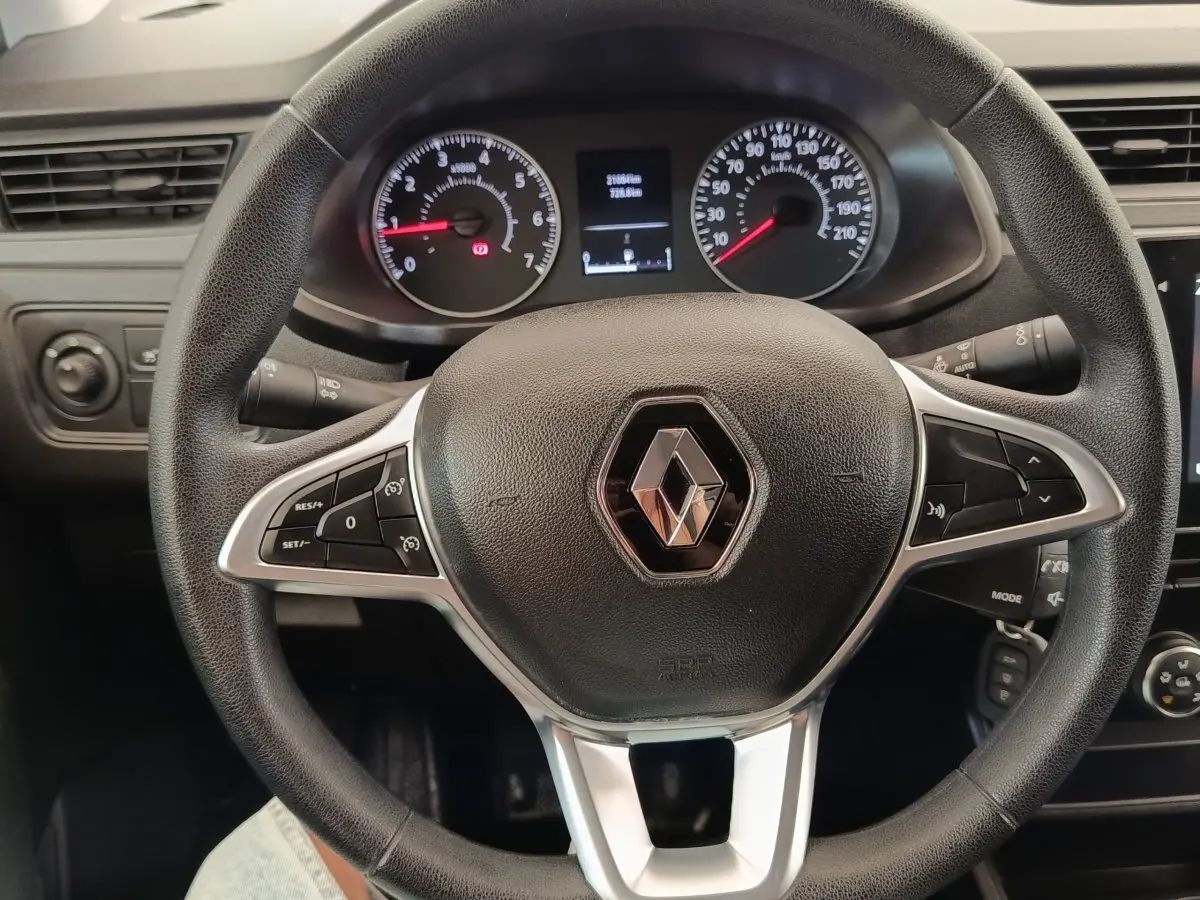 Vue rapprochée du volant multifonctions noir avec logo Renault, tableau de bord et compteurs visibles en arrière-plan.