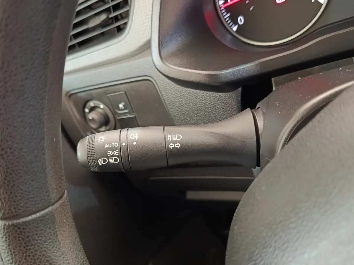 Gros plan sur la commande des phares et clignotants à gauche du volant dans l’habitacle noir du Renault Express blanc.