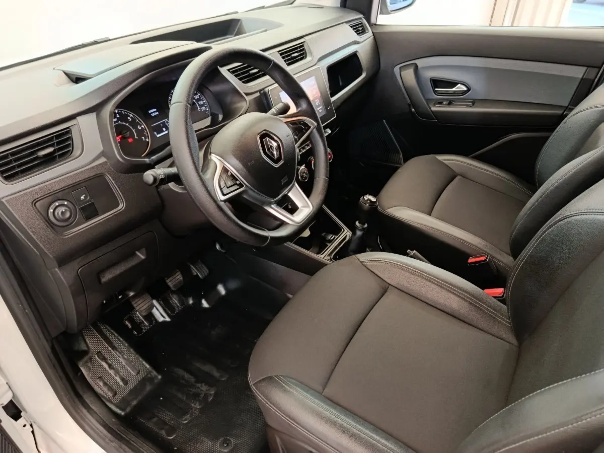 Vue intérieure côté conducteur du Renault Express blanc 2023, volant multifonctions et sièges noirs en tissu.