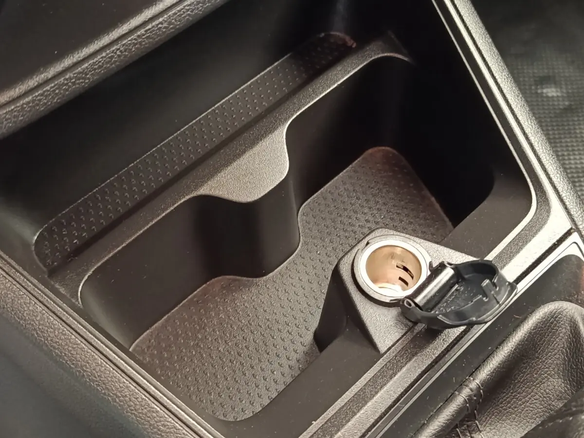 Gros plan sur la prise 12V ouverte et le rangement central noir dans l'habitacle du Renault Express blanc.